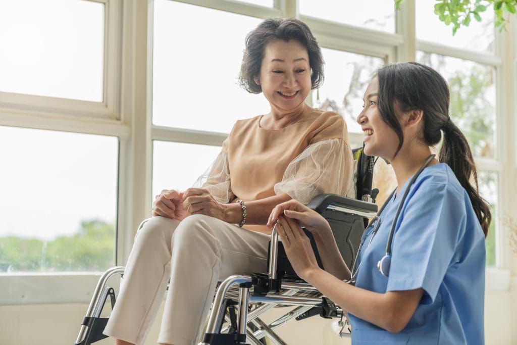 Lộ trình nghề nghiệp Điều dưỡng tại Đức - Chi tiết từ A-Z 1 asian young caregiver caring her elderly patient senior daycare handicap patient wheelchair hospital talking friendly nurse looking cheerful nurse wheeling senior patient